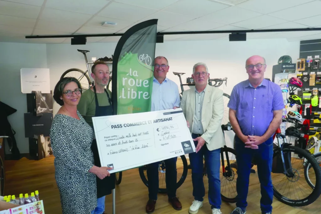 Des élus ont remis un grand chèque en carton au propriétaire d'un magasin de vélo.