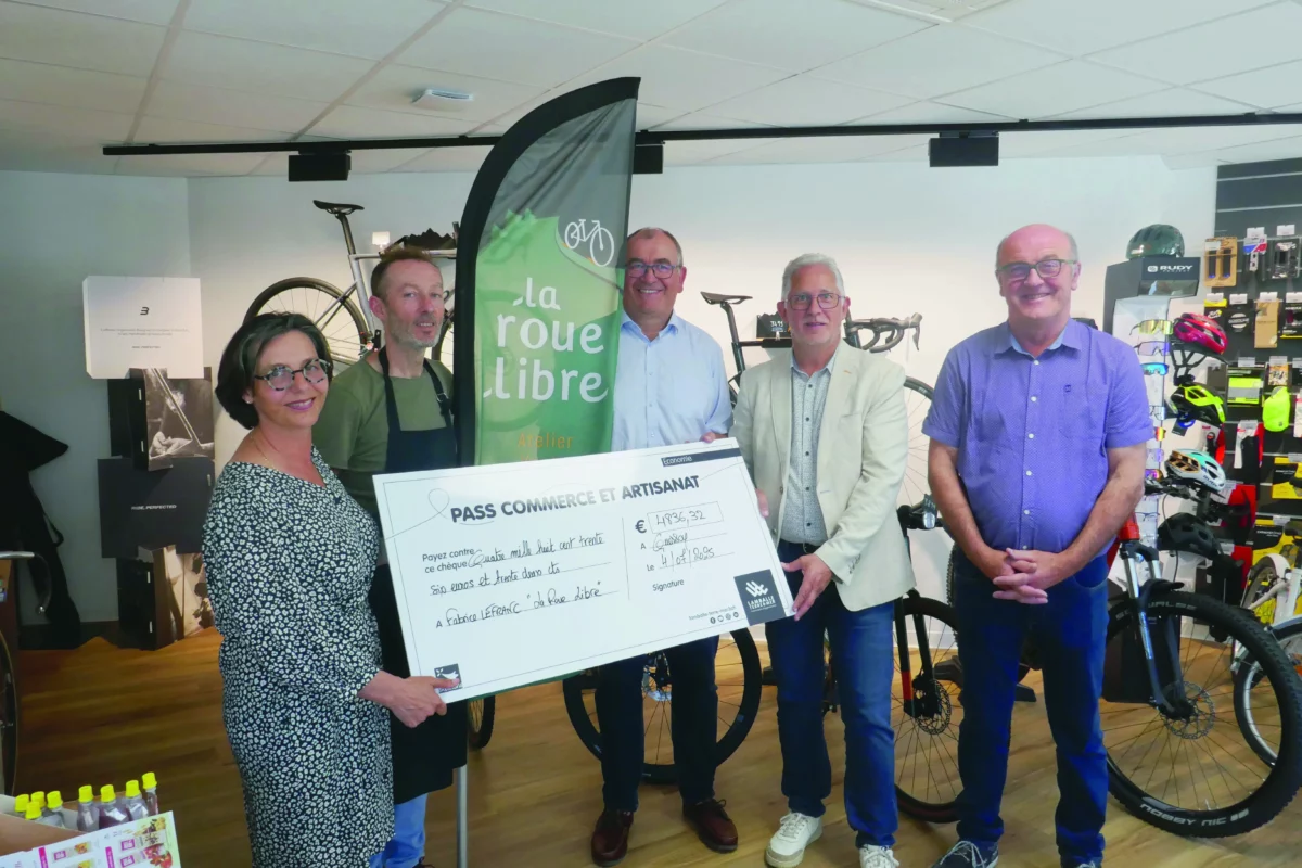 Des élus ont remis un grand chèque en carton au propriétaire d'un magasin de vélo.