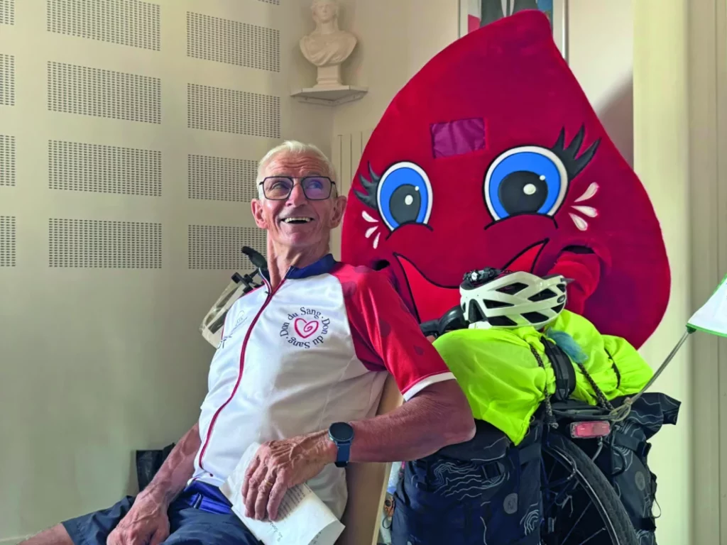 Robert Guyot aux côtés de son vélo et de la mascotte du don du sang.