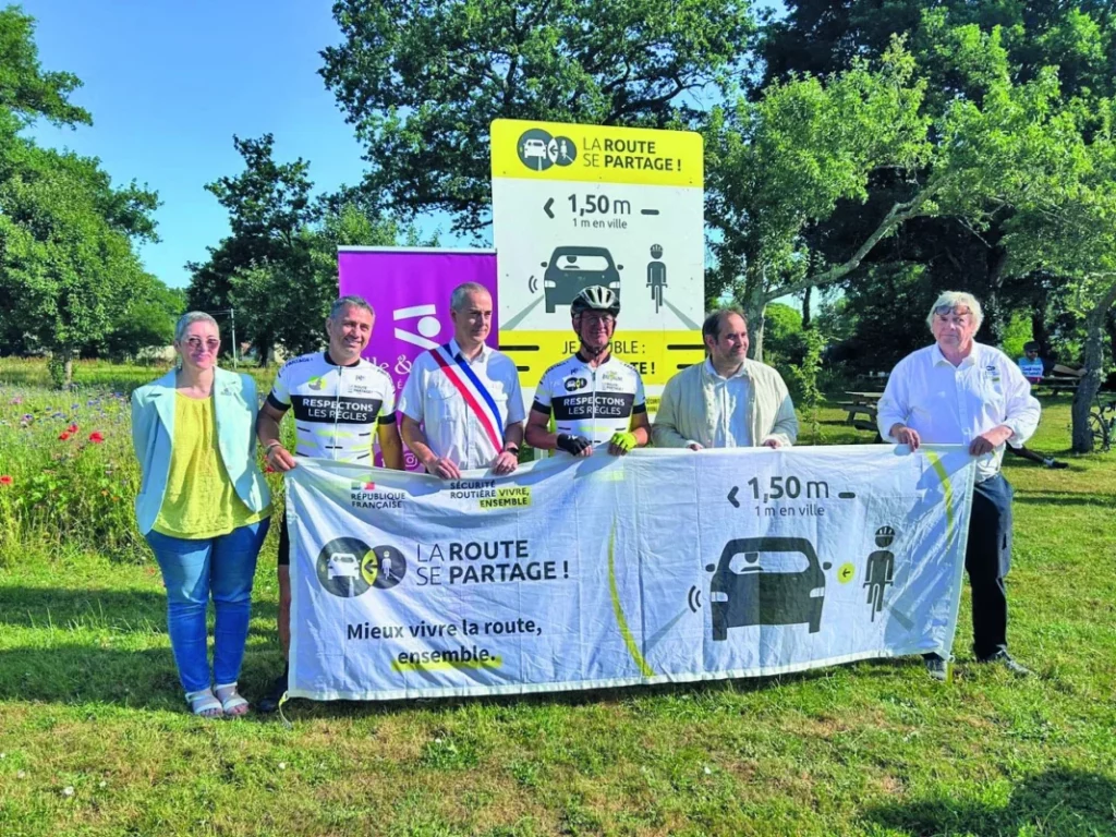 Le maire et des agents à côté d'un stand de reconnaissance de la route.