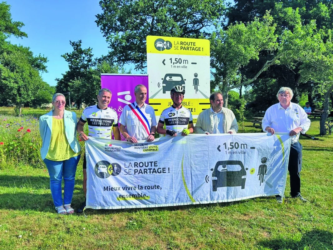 Le maire et des agents à côté d'un stand de reconnaissance de la route.