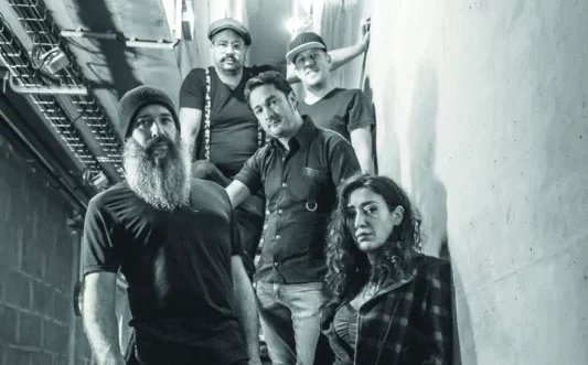 Un groupe de musique pose dans des escaliers.