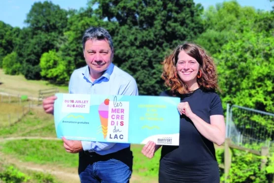 Deux organisateurs tiennent la pancarte publicitaire de l'événement.