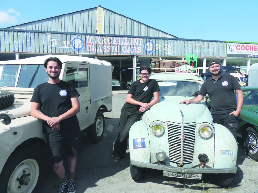 Les garagistes sont appuyés sur des vieilles voitures.