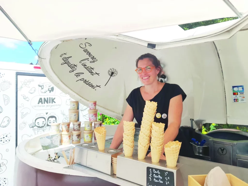 La patronne est dans sa caravane. Des cornets de glace sont exposés.