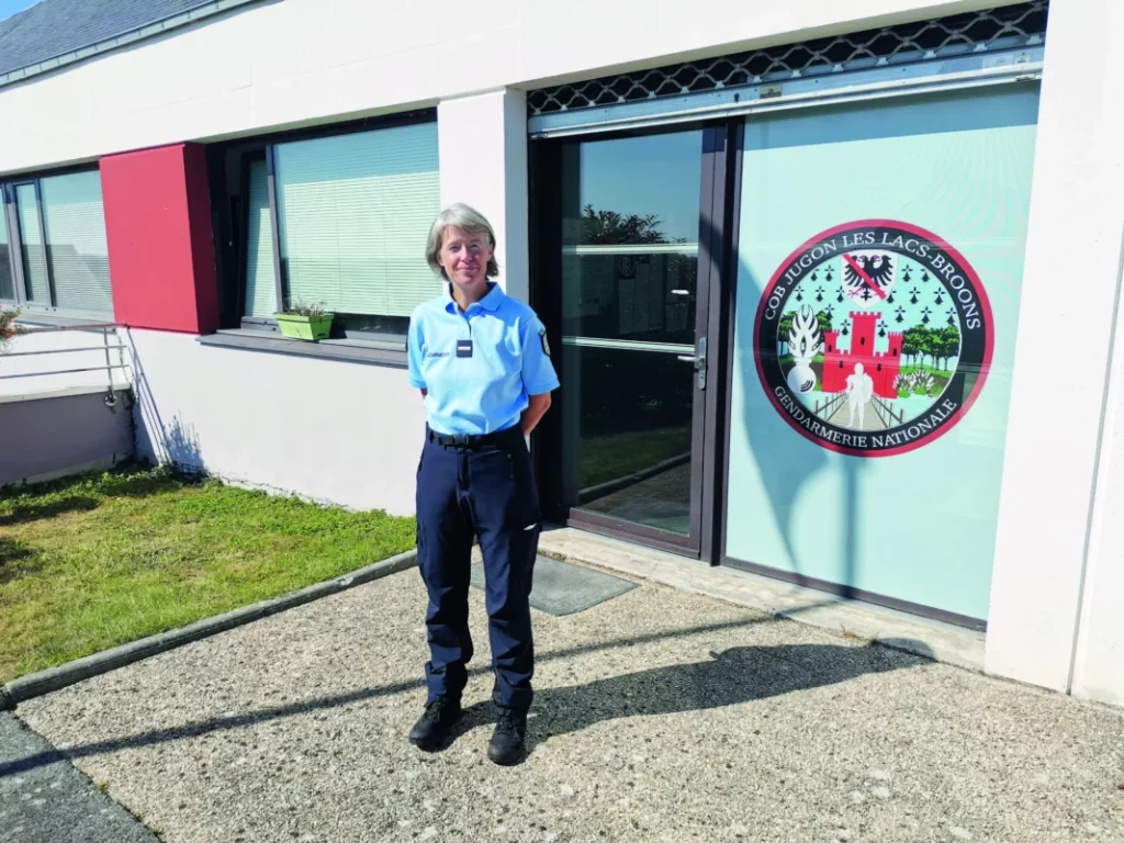 La gendarme se tient debout à côté du logo de la gendarmerie de la ville.