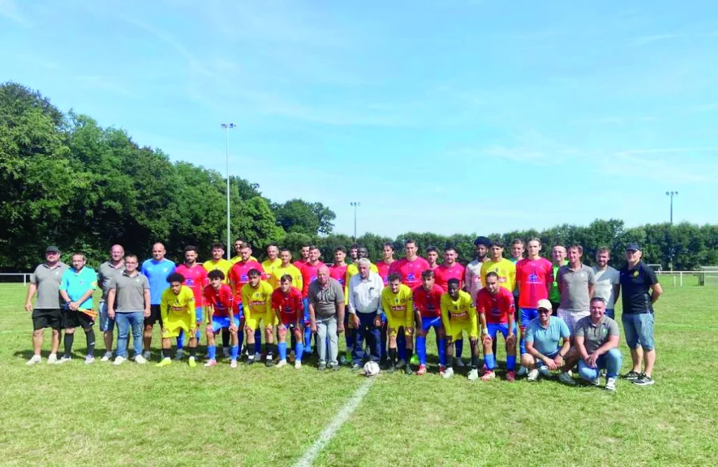 Les joueurs du club sont en groupe sur le terrain. Ils ont des maillots jaunes et rouges.