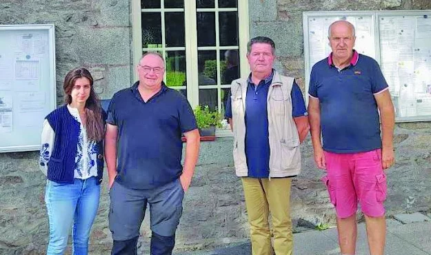 Quatre personnes posent devant un mur en pierre.