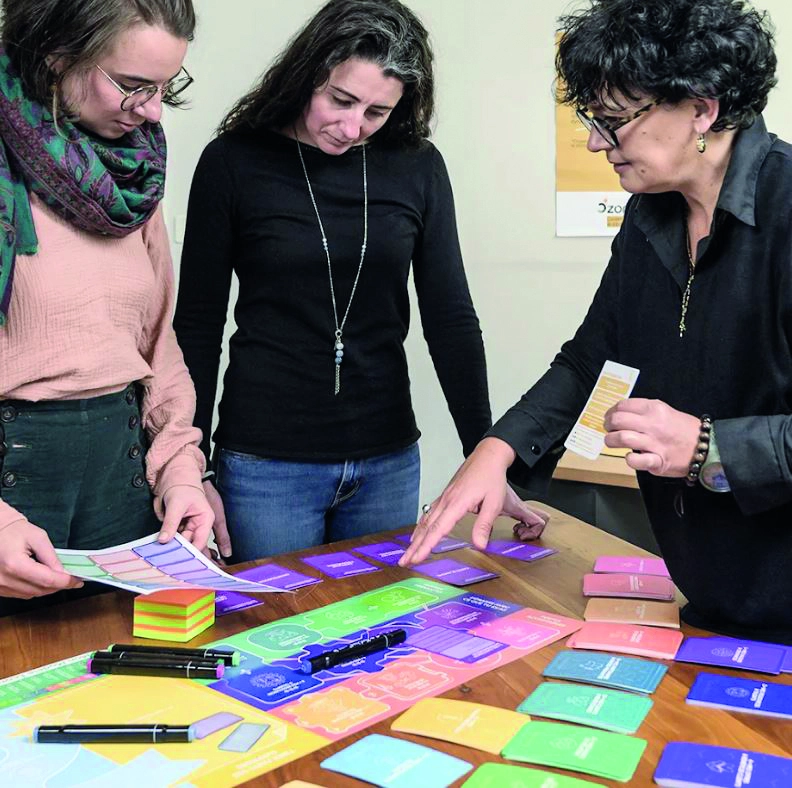 Trois femmes manipulent des cartes de couleur lors d'un atelier.