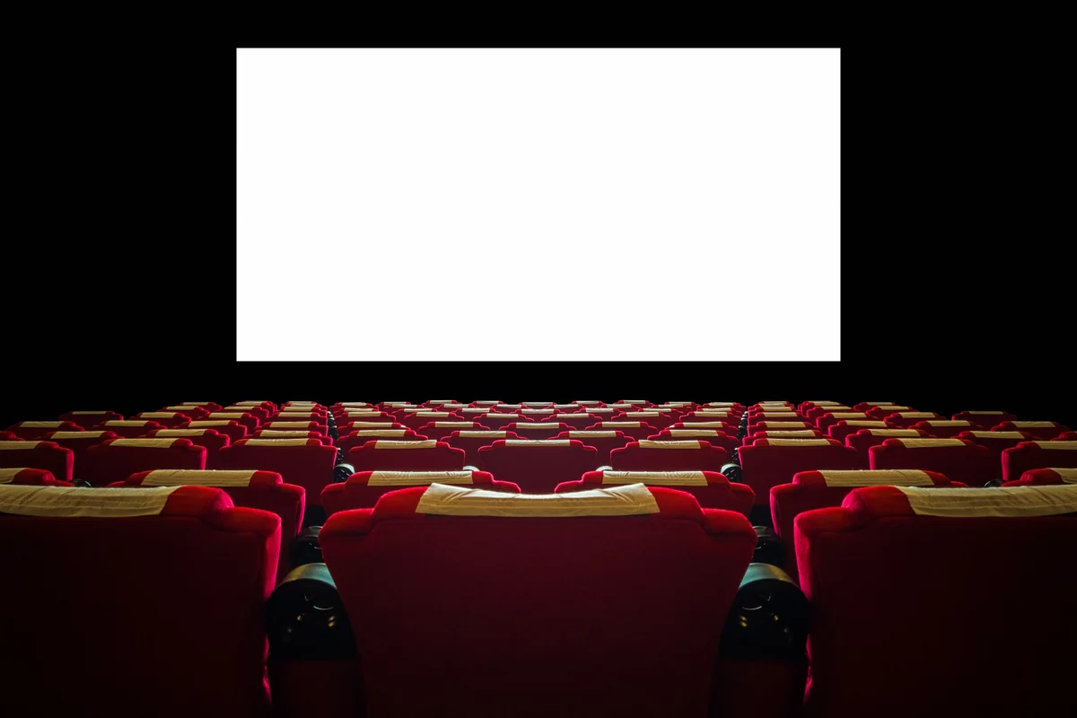 Une salle de cinéma avec un écran géant blanc et des fauteuils rouges.
